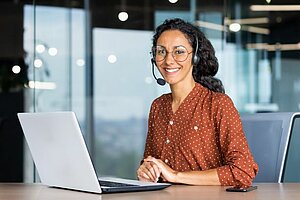 Frau mit Headset sitzt vor dem Computer